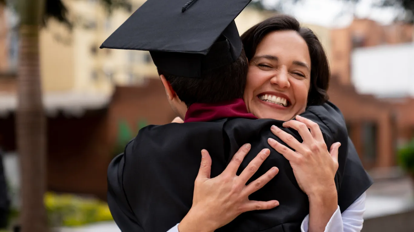 Una madre abraza a su hijo el día de su graduación universitaria: el resultado de años de previsión familiar