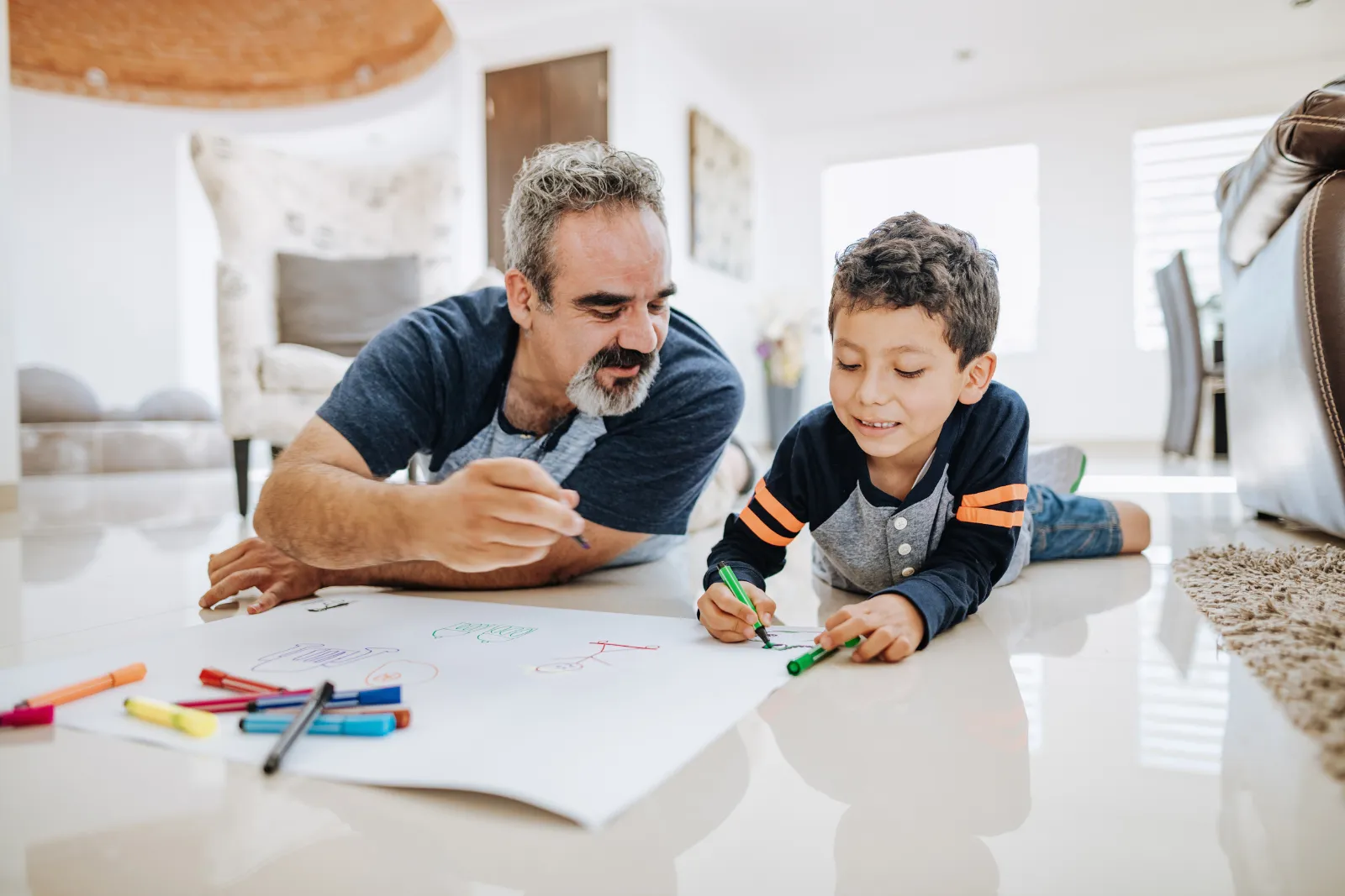 Padre dibujando con su hijo en casa, planeando el futuro
