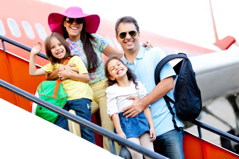 Familia con dos niñas bajando del avión al llegar de vacaciones