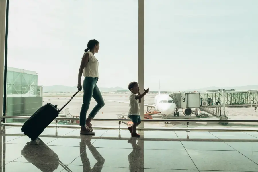 Mamá con su hijo mirando los aviones desde la sala del aeropuerto antes de salir de viaje