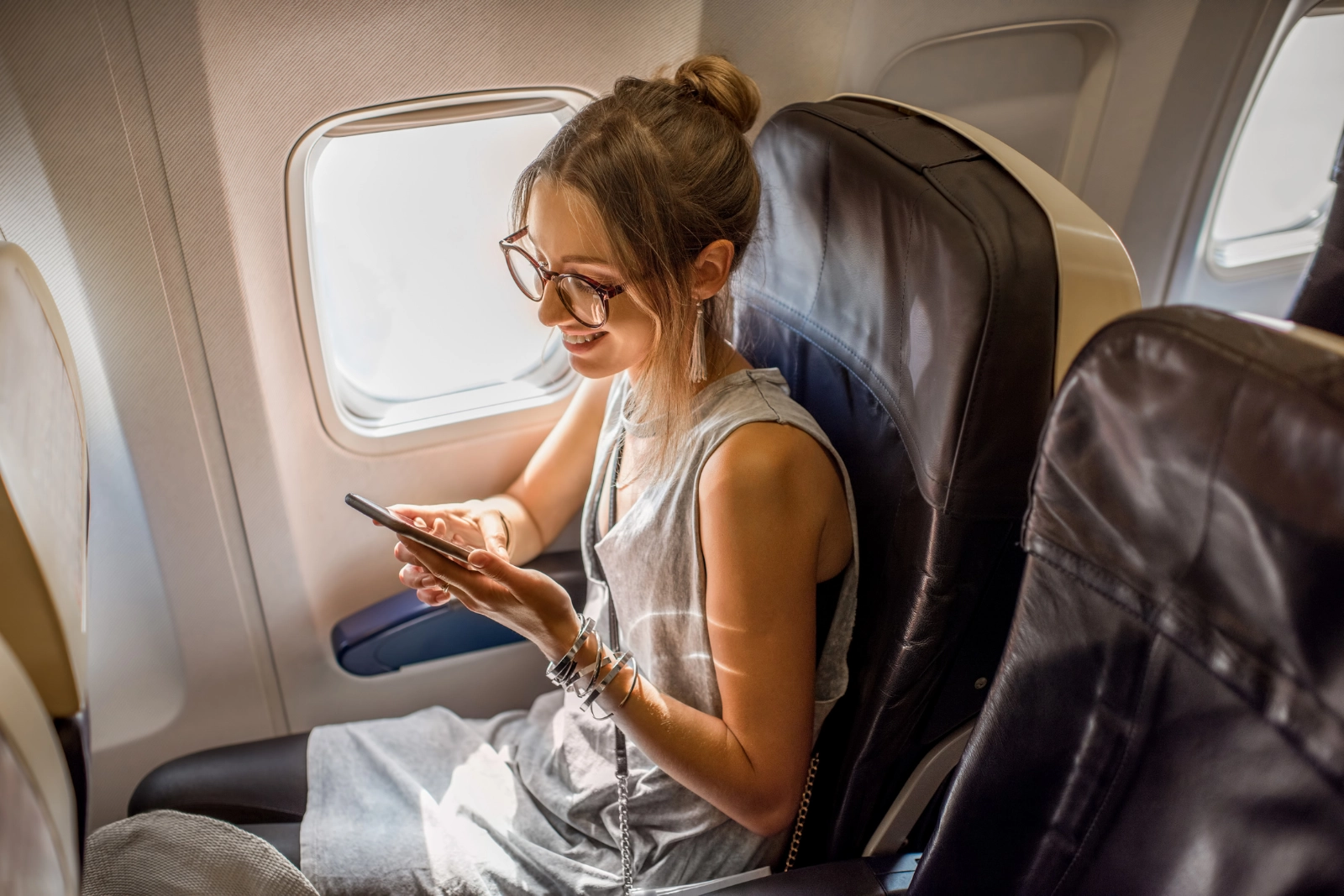 Viajera consultando su teléfono a bordo del avión