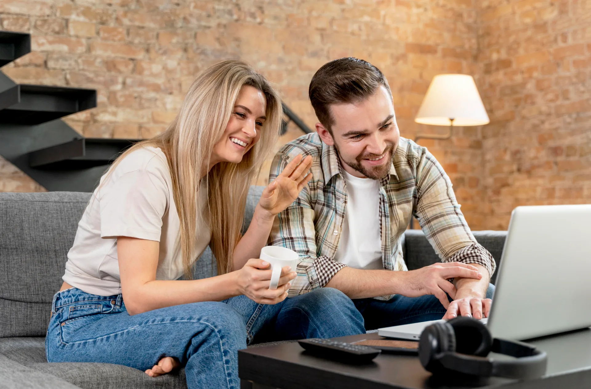 Pareja saludando en una videollamada desde la sala de su casa